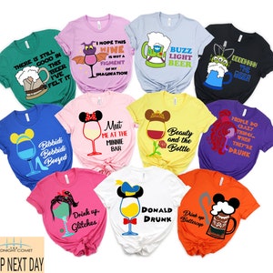 May include: A collection of 10 t-shirts featuring various Disney characters and alcohol-themed designs. The shirts are in different colors, including green, pink, blue, yellow, black, purple, and orange. The designs include a beer mug with a Star Wars character, a wine glass with a dragon, a beer mug with Buzz Lightyear, a beer mug with a character from Toy Story, a wine glass with Mickey Mouse ears, a wine glass with Belle, a wine glass with Ariel, a wine glass with Donald Duck, a wine glass with a character from The Princess and the Frog, and a beer mug with a character from Moana. The shirts are all printed with the text "There is still good in this beer I've felt it", "I hope this wine is not a figment of my imagination", "Buzz Light Beer", "Dooddhhh the beer", "Bibbidi Bobbidi Boozed", "Meet me at the Minnie Bar", "Beauty and the Bottle", "People do crazy things when they're drunk", "Drink up Glitches", "Donald Drunk", and "Drink up Buttercup".