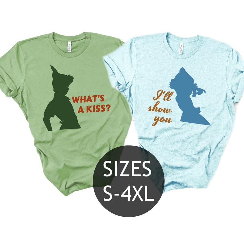 Peut inclure: Deux t-shirts, l'un vert et l'autre bleu, avec une silhouette de Peter Pan et Wendy. Le t-shirt vert dit "What's a kiss?" et le t-shirt bleu dit "I'll show you". Les t-shirts sont disponibles en tailles S-4XL.