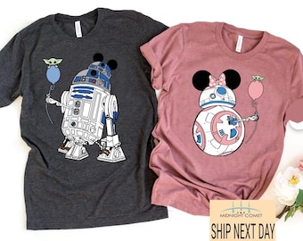 Könnte beinhalten: Zwei T-Shirts, eines dunkelgrau und eines rosa, mit einem Star Wars-Motiv. Das graue Shirt zeigt R2-D2 mit Mickey-Mouse-Ohren und einen kleinen Yoda, der einen Ballon hält. Das rosa Shirt zeigt BB-8 mit Minnie-Mouse-Ohren und einen kleinen Yoda, der einen Ballon hält. Beide Shirts haben den Text "Ship Next Day" unten.