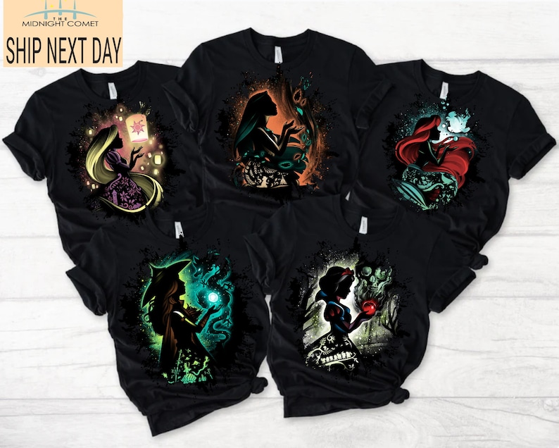 May include: Black t-shirts featuring colorful illustrations of fairytale characters. Each shirt showcases a different princess with unique designs, including a lantern, scissors, and a glowing orb. The shirts have the text "MIDNIGHT COMET SHIP NEXT DAY".