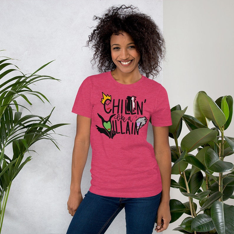 May include: A pink heather t-shirt with the text "Chillin' like a Villain" in black. The text is surrounded by images of Disney villains, including Maleficent, Ursula, and the Evil Queen.