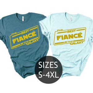 May include: Two light blue and teal t-shirts with a gold graphic that says "The Best Fiancé in the Galaxy". The graphic is in a Star Wars font. The shirts are available in sizes S-4XL.