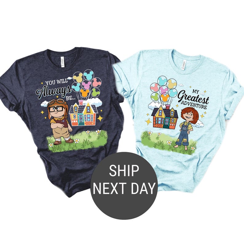 May include: Two t-shirts, one navy blue and one light blue, featuring cartoon graphics. The navy shirt has a character with goggles and the text "You Will Always Be...". The light blue shirt has a girl and the text "My Greatest Adventure". Both shirts have a house and balloons.