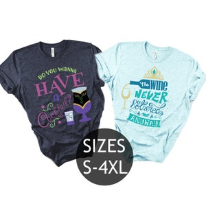 May include: Two t-shirts with a Frozen theme. The blue shirt says "Do you wanna have a cocktail?" with a cocktail glass and a shot glass. The light blue shirt says "The wine never bothered me anyway" with a wine glass and a bottle of wine.