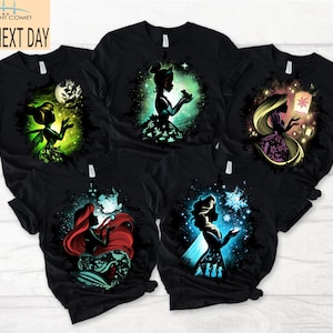 May include: Black t-shirts featuring colorful silhouette designs of popular fairytale characters. The shirts showcase characters like Tinkerbell, Ariel, and Rapunzel, with the text "MIDNIGHT COMET SHIP NEXT DAY" in the upper left corner.