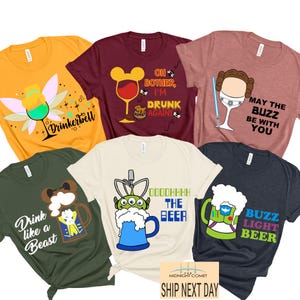 Op de afbeelding: Een verzameling kleurrijke grafische t-shirts. Ontwerpen omvatten een fee met een cocktail, een wijnglas met muisoren, een Star Wars-personage en bierthema-afbeeldingen. De shirts zijn in verschillende kleuren, waaronder geel, bordeauxrood en groen.