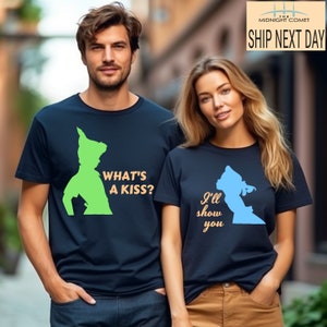 Peut inclure: Un ensemble de t-shirts assortis pour un couple, avec des silhouettes de Peter Pan et Wendy du film Disney Peter Pan. Le t-shirt de l'homme dit "What's a kiss?" en orange et le t-shirt de la femme dit "I'll show you" en orange.