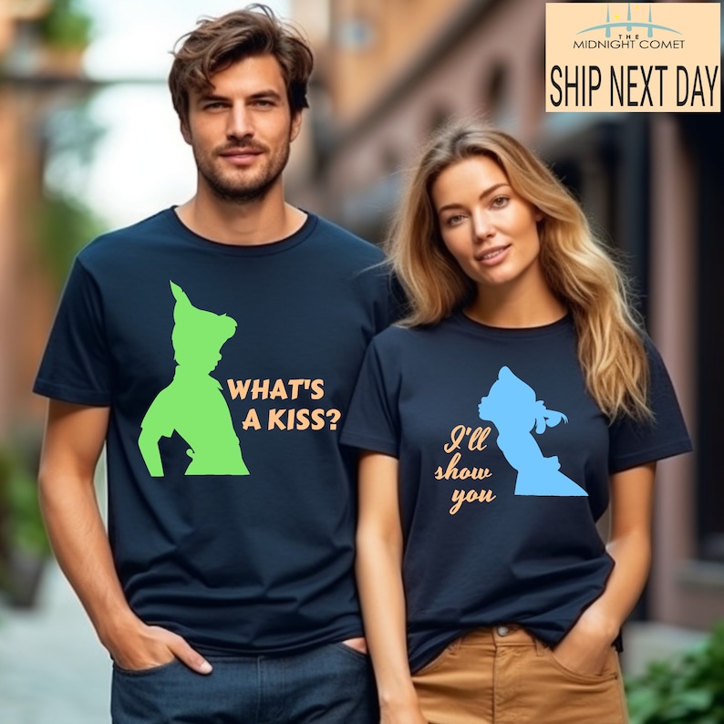 Peut inclure: Un ensemble de t-shirts assortis pour un couple, avec des silhouettes de Peter Pan et Wendy du film Disney Peter Pan. Le t-shirt de l'homme dit "What's a kiss?" en orange et le t-shirt de la femme dit "I'll show you" en orange.