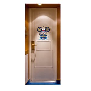 May include: A white door with a Mickey Mouse-shaped sign that reads "Our First Disney Cruise" and "The [Family Name] Family 2020." The sign features a cruise ship illustration and the word "Adventure" in blue.