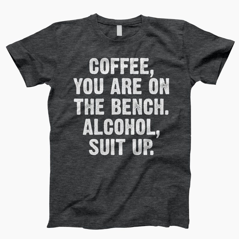 May include: Dark gray t-shirt with white text that reads "Coffee, you are on the bench. Alcohol, suit up."