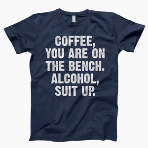 May include: Navy blue t-shirt with white text that reads "Coffee, you are on the bench. Alcohol, suit up."