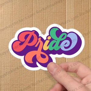 May include: A sticker with the word "Pride" written in rainbow colors with a purple background.