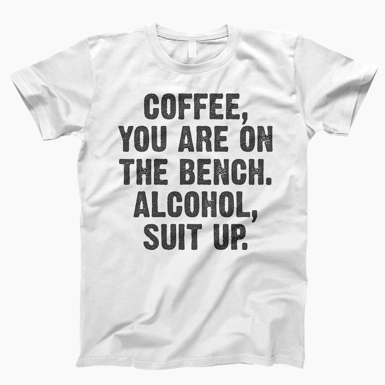 May include: White t-shirt with black text that reads "Coffee, you are on the bench. Alcohol, suit up."