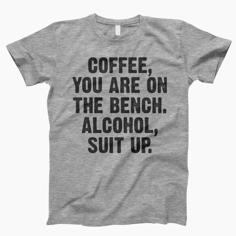 May include: Gray t-shirt with the text "Coffee, you are on the bench. Alcohol, suit up."