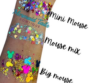 Puede incluir: Primer plano de cuatro tipos diferentes de purpurina con formas de Mickey Mouse. La purpurina está etiquetada como "Mini Mouse", "Mouse Mix", "Big Mouse" y "Mermaid Tails Boutique".