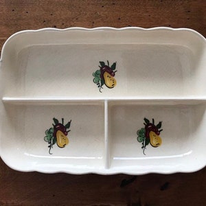 May include: A white ceramic serving dish with four sections. Each section has a hand-painted design of a pear with green leaves and a red stem.