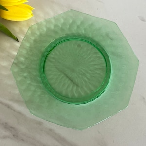 May include: A green glass octagonal plate with a smaller, round, green glass plate in the center. The plate has a textured surface.