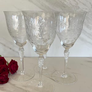 May include: Set of three clear glass wine glasses with a cut glass design. The glasses have a tall, slender stem and a wide bowl.