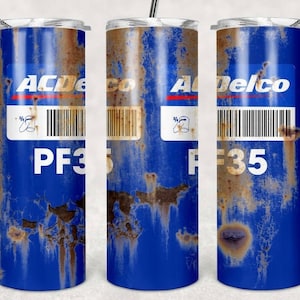 Peut inclure: Trois gobelets en acier inoxydable avec un design bleu et brun rouillé. Les gobelets présentent une étiquette blanche avec le texte "ACDelco" et un code-barres. Le texte "PF35" est imprimé sous l'étiquette.