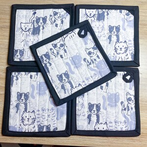 May include: Set of four black and white cat print fabric pot holders with black trim.
