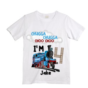 May include: White t-shirt with a blue train engine graphic, the text "CHUGGA CHUGGA CHOO CHOO I'M 4 Jake" and a cloud shape.