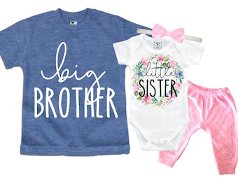 May include: A blue t-shirt with the text "big brother" in white lettering and a white onesie with the text "little sister" in black lettering surrounded by a floral wreath. The onesie is paired with pink pants.