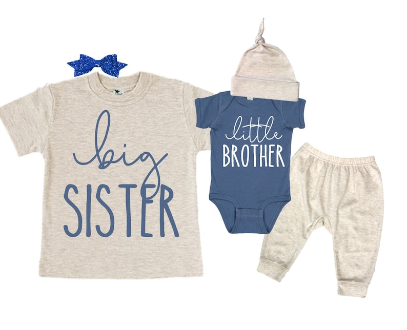 May include: A set of two baby outfits, one for a big sister and one for a little brother. The big sister outfit is a beige t-shirt with the words "big sister" printed in blue. The little brother outfit is a blue bodysuit with the words "little brother" printed in white, and a beige hat.