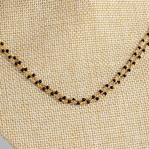 May include: A double strand necklace with black beads and a gold chain.