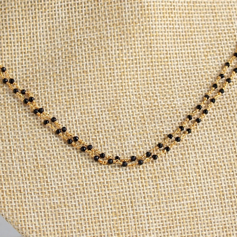 May include: A double strand necklace with black beads and a gold chain.