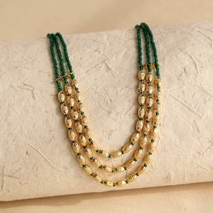 May include: A three-strand necklace with gold oval beads and green spacer beads.