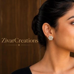 Puede incluir: Primer plano de una mujer que lleva pendientes con forma de flor. Los pendientes son dorados con múltiples piedras preciosas transparentes. El texto "ZivarCreations" se muestra en letras doradas.