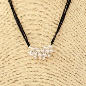 May include: A black beaded necklace with a silver charm pendant. The charm is a cluster of small, round silver beads.