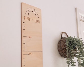 May include: A wooden growth chart with a sun design and the names "Pippa + Liam" at the top. The chart has markings for height in centimeters, with numbers 160, 170, and 180 visible.