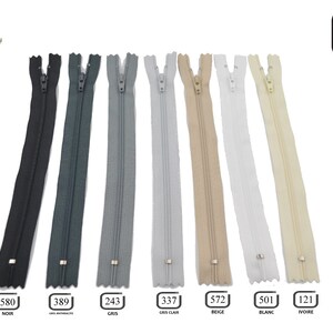 May include: A set of seven 30-inch zipper closures in various colors, including black, gray, light gray, beige, white, and ivory. The zippers are labeled with their corresponding color names and numbers.