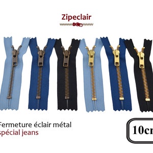 Può includere: Assortimento di sei cerniere metalliche da 10 cm in blu, nero e blu chiaro. Le cerniere hanno denti dorati e un cursore metallico. Il testo "Fermeture éclair métal spécial jeans" e "10cm" è visibile nell'immagine.