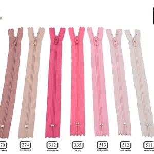 May include: Seven pink zipper closures, each 30 inches long, with a silver slider. The zippers are labeled with numbers and color names in French: 070 Vieux Rose, 274 Rose Saumon, 312 Rose Fuschia, 335 Rose, 513 Rose Bonbon, 512 Rose Drag&eacute;e, 511 Rose Bebe.