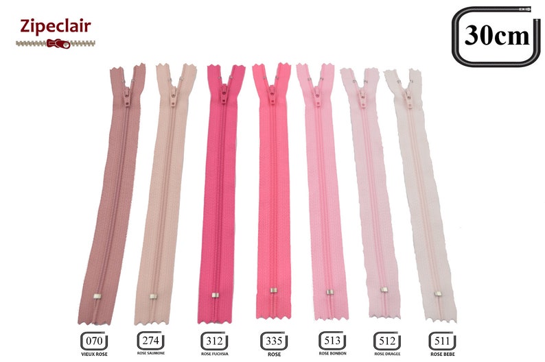 May include: Seven pink zipper closures, each 30 inches long, with a silver slider. The zippers are labeled with numbers and color names in French: 070 Vieux Rose, 274 Rose Saumon, 312 Rose Fuschia, 335 Rose, 513 Rose Bonbon, 512 Rose Drag&eacute;e, 511 Rose Bebe.