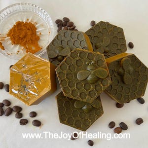 Può includere: Primo piano di sei saponette a forma esagonale. Il sapone è verde e marrone con un motivo a nido d'ape e un disegno di un'ape. Sullo sfondo c'è una piccola ciotola con una polvere gialla. Il testo "www.TheJoyOfHealing.com" è in basso nell'immagine.