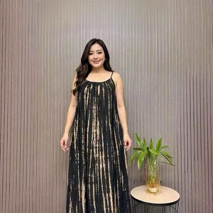 May include: A floor-length black sleeveless dress featuring a vertical tie-dye pattern in shades of beige and tan. The garment has thin spaghetti straps, a rounded neckline, and a loose, flowing silhouette that extends to the floor.