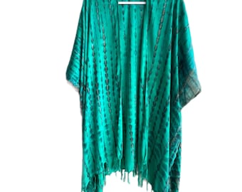 May include: A green tie-dye kimono-style cover-up with fringe along the bottom hem. The open-front garment is hanging on a white hanger against a white background. The fabric has vertical streaks of dark green and black.
