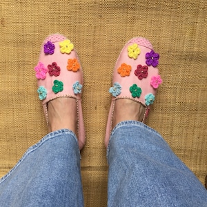 May include: Pink canvas espadrilles with colorful crocheted flower embellishments.