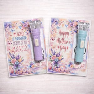 May include: Two Mother's Day cards with a flashlight attached. One card reads "My world is brighter because of you! Happy Mother's Day." The other card says "Happy Mother's Day." The flashlights are purple and blue.