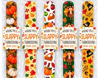 May include: Five slap bracelets in clear plastic packaging, each featuring Thanksgiving-themed patterns like pumpkins, autumn leaves, turkeys, and pies. Each bracelet has a paper tag printed with the text: WISHING YOU A SLAPPY THANKSGIVING FROM: COLT.