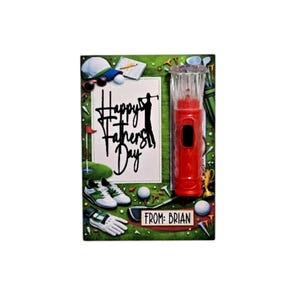 Pu&ograve; includere: Un biglietto per la festa del pap&agrave; con elementi a tema golf. Il biglietto presenta un pulitore per mazze da golf rosso, scarpe da golf, una pallina da golf e la scritta "Happy Father's Day". Il biglietto &egrave; firmato "From: Brian".