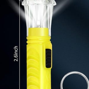 Pu&ograve; includere: Una torcia a LED giallo brillante con una testa trasparente e strutturata, alta 6,6 cm. La torcia ha un pulsante di accensione nero e un portachiavi argentato. La luce brilla intensamente.
