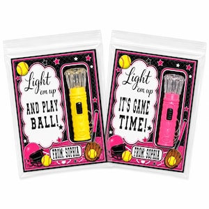 May include: Two clear plastic favor bags containing a small flashlight keychain. One bag features a yellow flashlight with text reading Light em up AND PLAY BALL! and the other a pink flashlight with text reading Light em up IT'S GAME TIME!