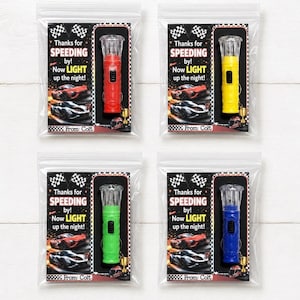 May include: Four small plastic bags each containing a flashlight in red, yellow, green, and blue. Each bag has a card with the text "Thanks for SPEEDING by! Now LIGHT up the night!" and a race car graphic.