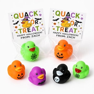 May include: Two clear plastic bags containing rubber ducks with header cards reading QUACK OR TREAT HAPPY HALLOWEEN FROM ZACH. Four loose rubber ducks in orange, purple, black, and green are arranged in front, featuring spiderweb, jack-o-lantern, bat, and skull designs.