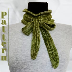 Peut inclure: Écharpe verte tricotée, présentée avec un nœud. L'écharpe est exposée sur un mannequin, mettant en valeur sa texture et sa forme. Le mot "Pattern" est affiché verticalement sur le côté gauche de l'image.