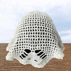 Peut inclure: Un chapeau en crochet blanc avec un motif en dentelle. Le chapeau a un large bord et une bordure festonn&eacute;e.